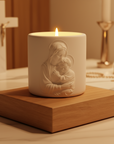 White candle with Virgin Mary and Child on a wooden base in a religious setting