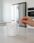 Person lighting a white candle with a match in a kitchen setting