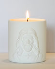 White ceramic jar with embossed face design on a beige surface