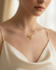 Woman wearing a gold necklace with a dove holy spirit pendant in a softly lit room.