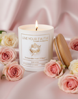 Immaculate heart of Mary prayer candle in a satin blush background and surrounded by roses.