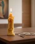 Yellow candle with a religious figure of Saint Therese on a wooden table, with a blurred background