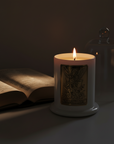 Candle with decorative label of Saint Michael the Archangel next to an open book in a dark setting