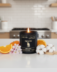 Agnus Dei Candle in a 'Live Your Faith' container on a kitchen counter with oranges and cotton.