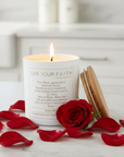 Candle with Ave Maria prayer, surrounded by red rose petals on a light surface.