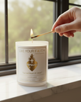 Candle labeled 'Live Your Faith' being lit by a match on a windowsill.