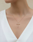 Gold cross necklace on a mannequin with a white top