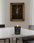 Candle in a black container with 'Live Your Faith' branding on a table with the words "I thirst"