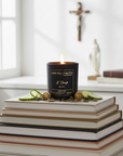 Candle in a black container with 'Live Your Faith' branding and words I thirst on a pile of books