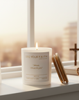 White candle with "Jesus I trust in you" label on a white background