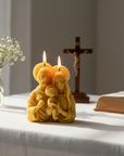 Candle shaped like a Holy family with a cross and bible in the background