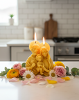 Yellow Beeswax Holy family-shaped candle on a kitchen counter with flowers.