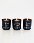 Three black candles with white text on a white background