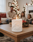 Decorative candle on a coffee table with people sitting in the background in a festive living room.