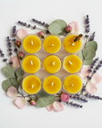Nine yellow candles in a 3x3 grid on a white background with flowers