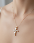 Gold necklace with a pearl pendant on a person wearing a white top.