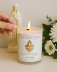 Sacred Heart Of Jesus Candle with flowers and a hand lighting it.