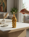 Person lighting a candle shaped like Saint Joseph on a table in a living room.