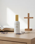 White spray bottle with gold cap on a white background inspired by Saint Teresa of Avila.