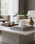 Modern living room with a marble coffee table, books, a catholic Virgin Mary and Jesus candle, and a vase.
