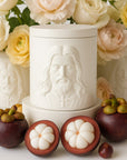 Catholic Candle in a white vessel with the holy Face of Jesus surrounded by fruits and flowers