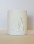 White ceramic jar with embossed face design on a beige surface