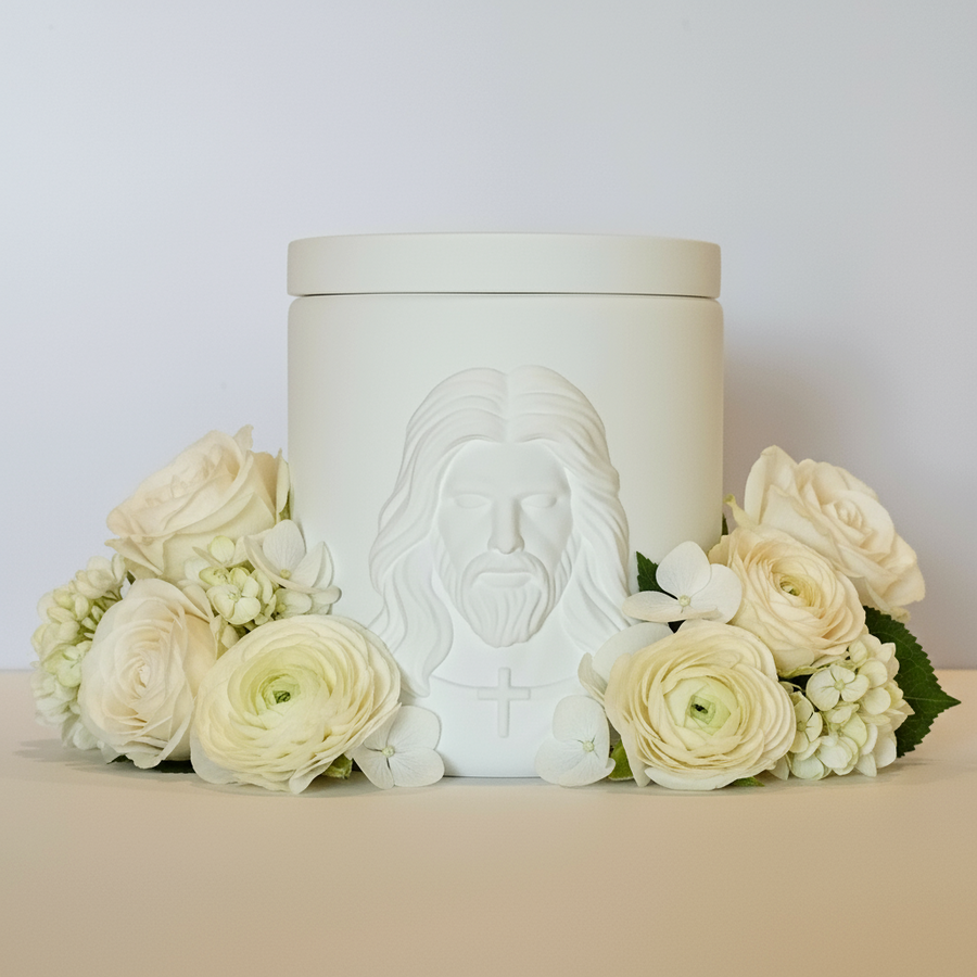 White ceramic jar with embossed face design on a beige surface with flowers
