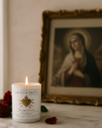 Candle with image of the sorrowful heart in front of a Virgin Mary religious painting