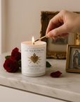 Our Lady of Sorrows catholic prayer candle being lit with a match, surrounded by roses and religious-themed decor.