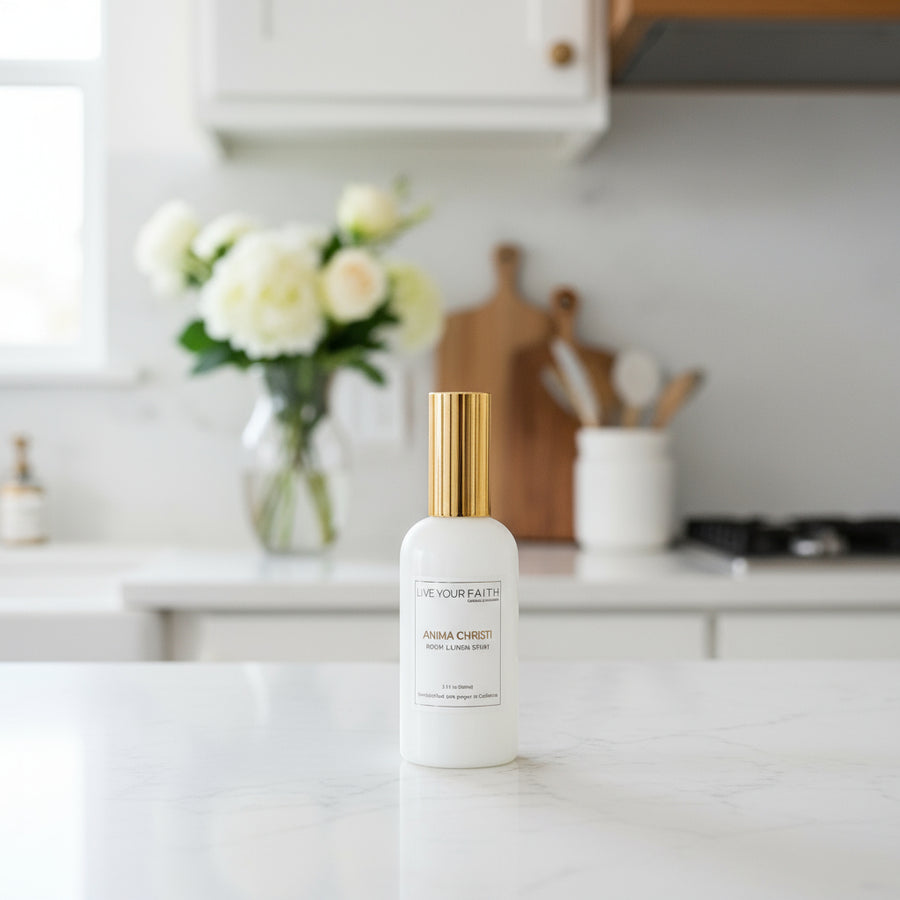 White room spray bottle with gold cap on a kitchen counter. Anima Christi catholic room spray.