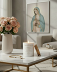 Ave Maria Catholic Candle on a coffee table with a vase of roses and a painting in the background