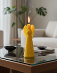 Yellow angel-shaped candle on a glass coffee table in a living room.