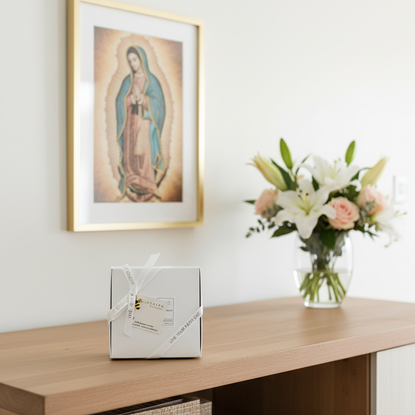 Framed religious artwork above a wooden console table with a vase of flowers and a gift box.