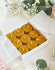 Box of beeswax candles surrounded by pink and white roses on a light background