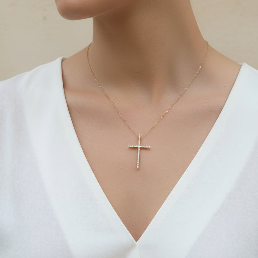 Gold cross necklace on a mannequin with a white top