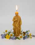 Beeswax candle shaped like Saint Joseph with flowers and a bee on a white background