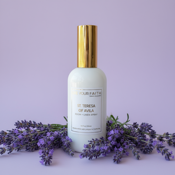 Room spray bottle with gold cap and lavender flowers on a light purple background inspired by Saint Teresa of Avila.