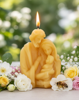 Beeswax Holy family-shaped candle with a bee and flowers on a blurred green background