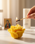 Hand lighting a beeswax rose shaped candle with a match, blurred background