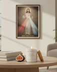 Catholic Prayer Candle with the Surrender Novena Prayer in sweet fig scent on a table in a room with an image of Jesus  on the wall.
