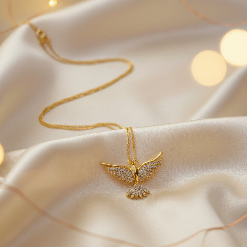 Gold necklace with a dove shaped pendant on a soft fabric background